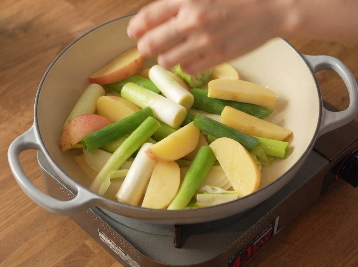 Lanières de poitrine de porc crues assaisonnées placées solidement sur la couche de légumes à lintérieur de la cocotte.
