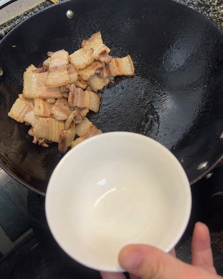 Excès dhuile retiré du wok à laide dune spatule et versé dans un bol blanc.