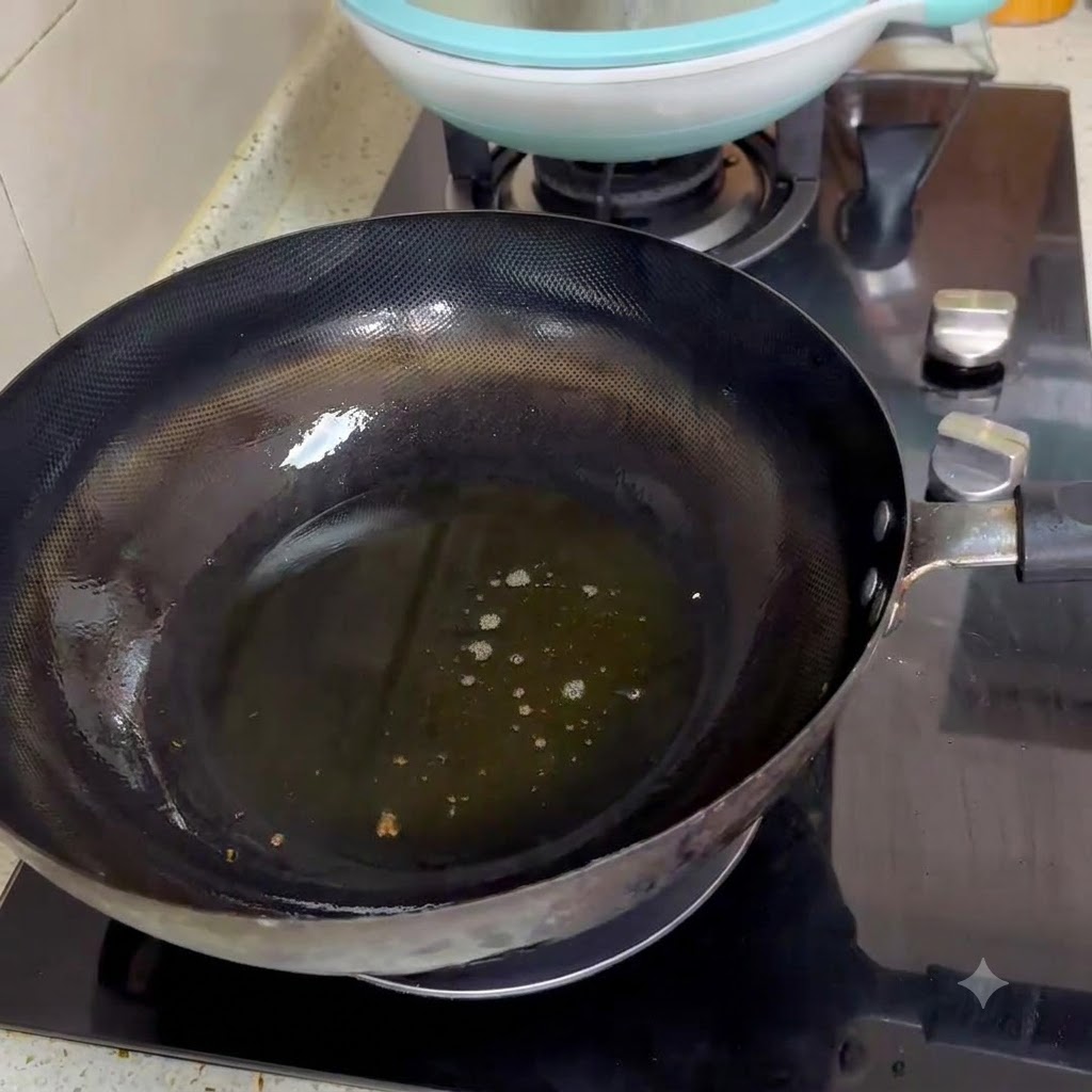 Deux cuillerées de pâte de haricots piquante en train de frire dans de lhuile chaude à lintérieur dun wok noir.