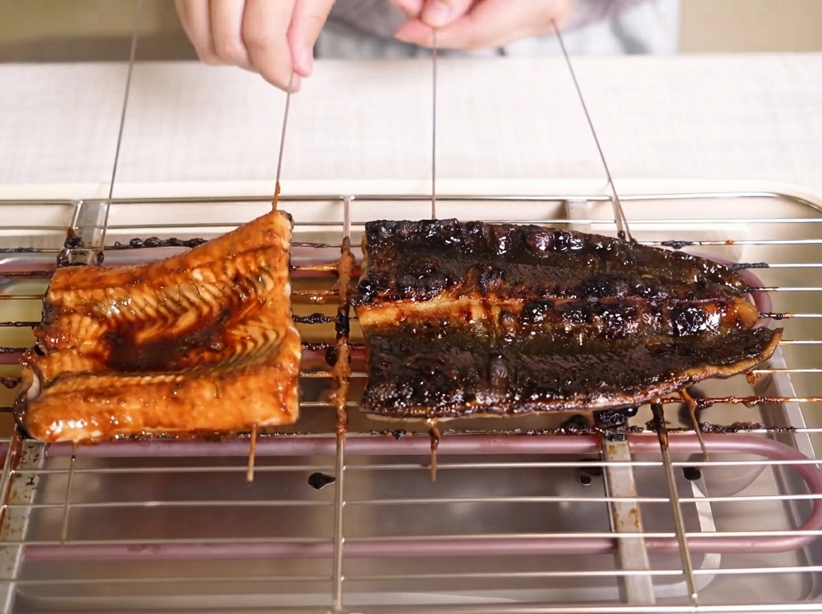 Des filets danguille dorés badigeonnés dune sauce sombre et brillante sur une grille.