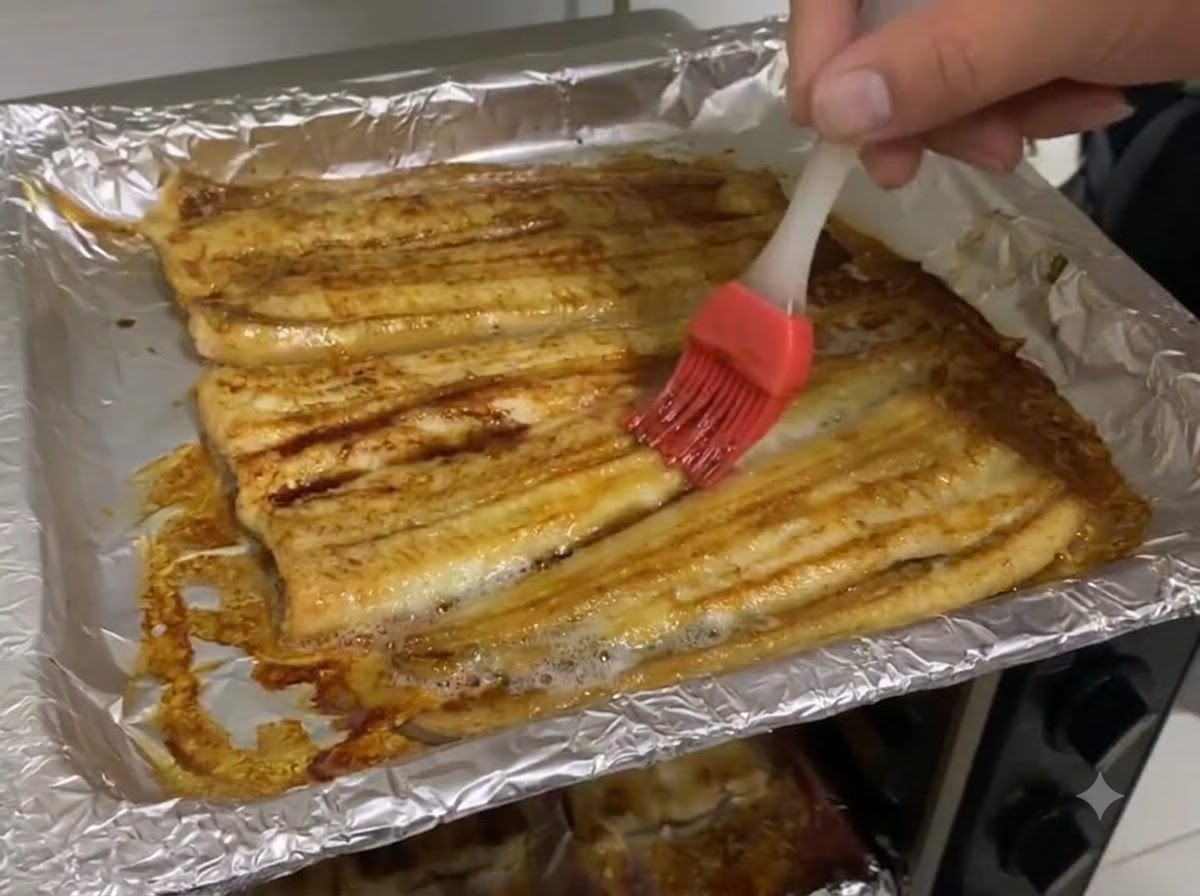Sauce soja noire étalée au pinceau sur la surface de languille cuite dans la plaque de cuisson.