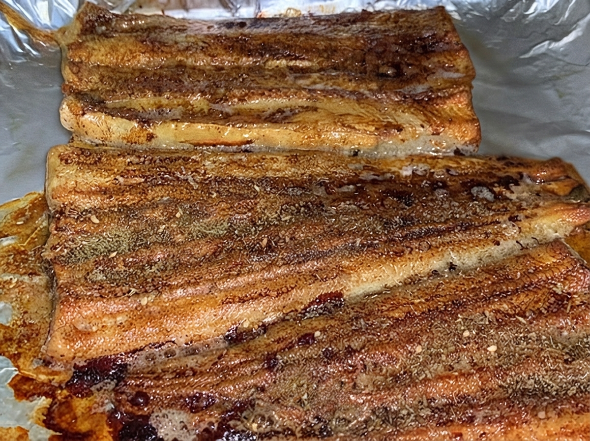 Filets danguille cuits saupoudrés uniformément dépices BBQ brunes dans la plaque de cuisson.
