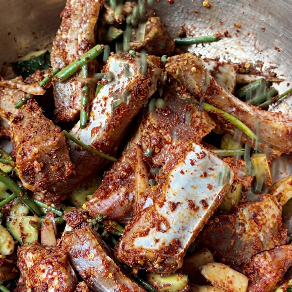 Une poignée de grains de poivre vert entiers du Sichuan tombant sur les côtes de porc marinées.