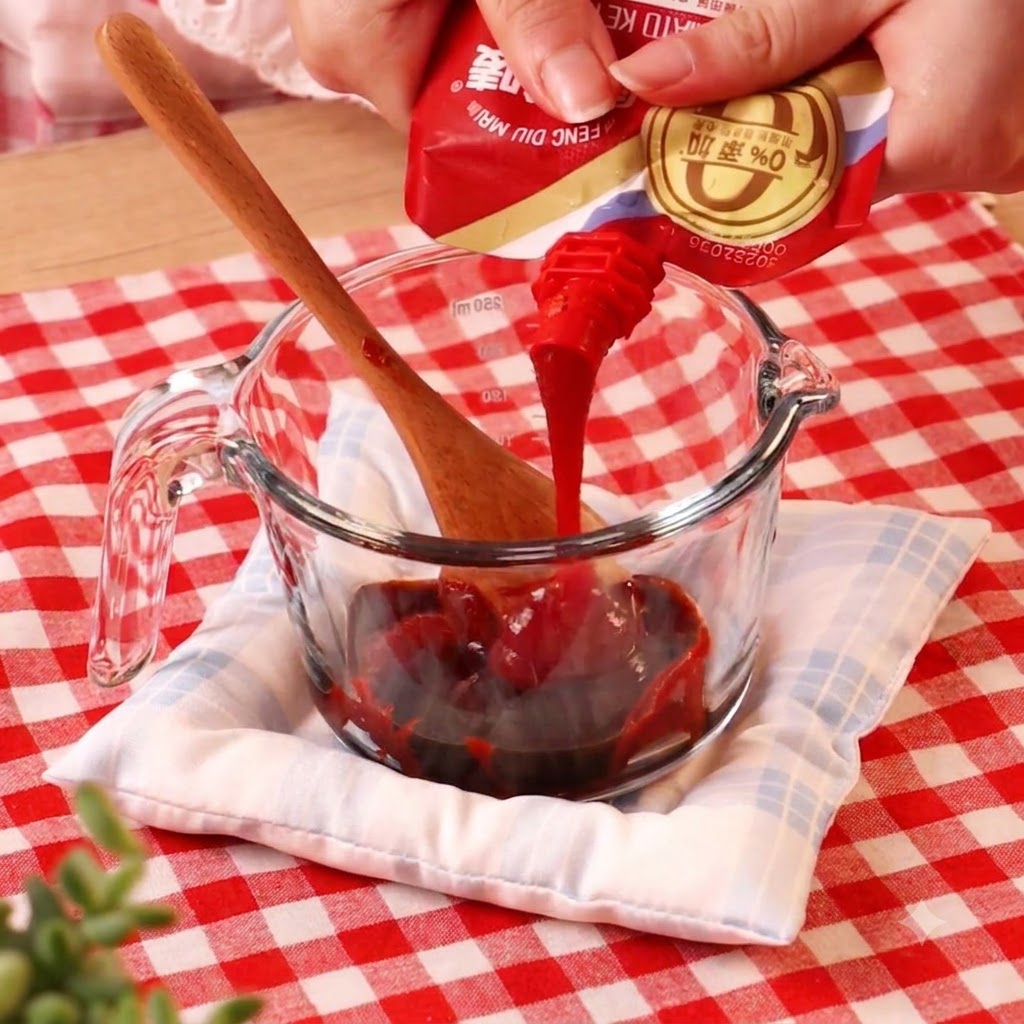 De la pâte de piment versée à partir dun sachet dans un verre mesureur contenant dautres liquides.