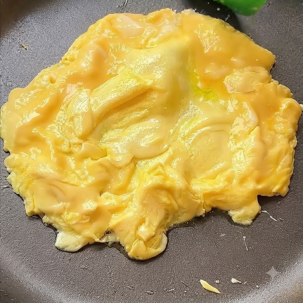 Des œufs poussés vers le centre dune poêle à laide dune spatule.