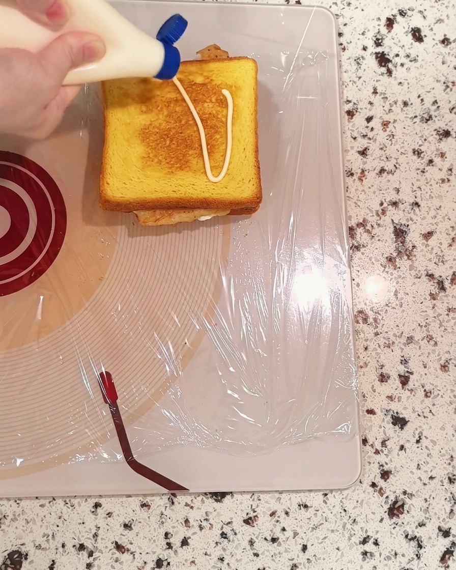 De la mayonnaise pressée en motif de zigzag sur une tranche de pain grillé.