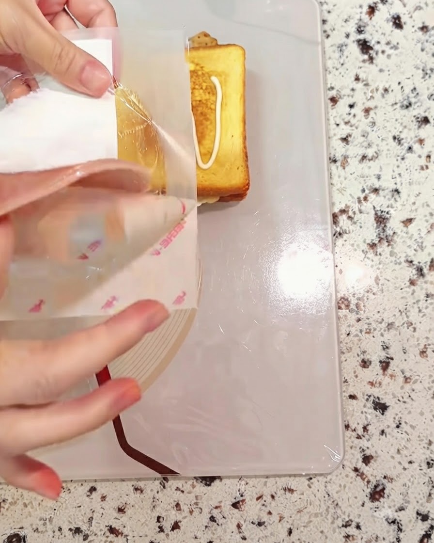 Une tranche de jambon déposée sur le pain du sandwich en cours dassemblage.