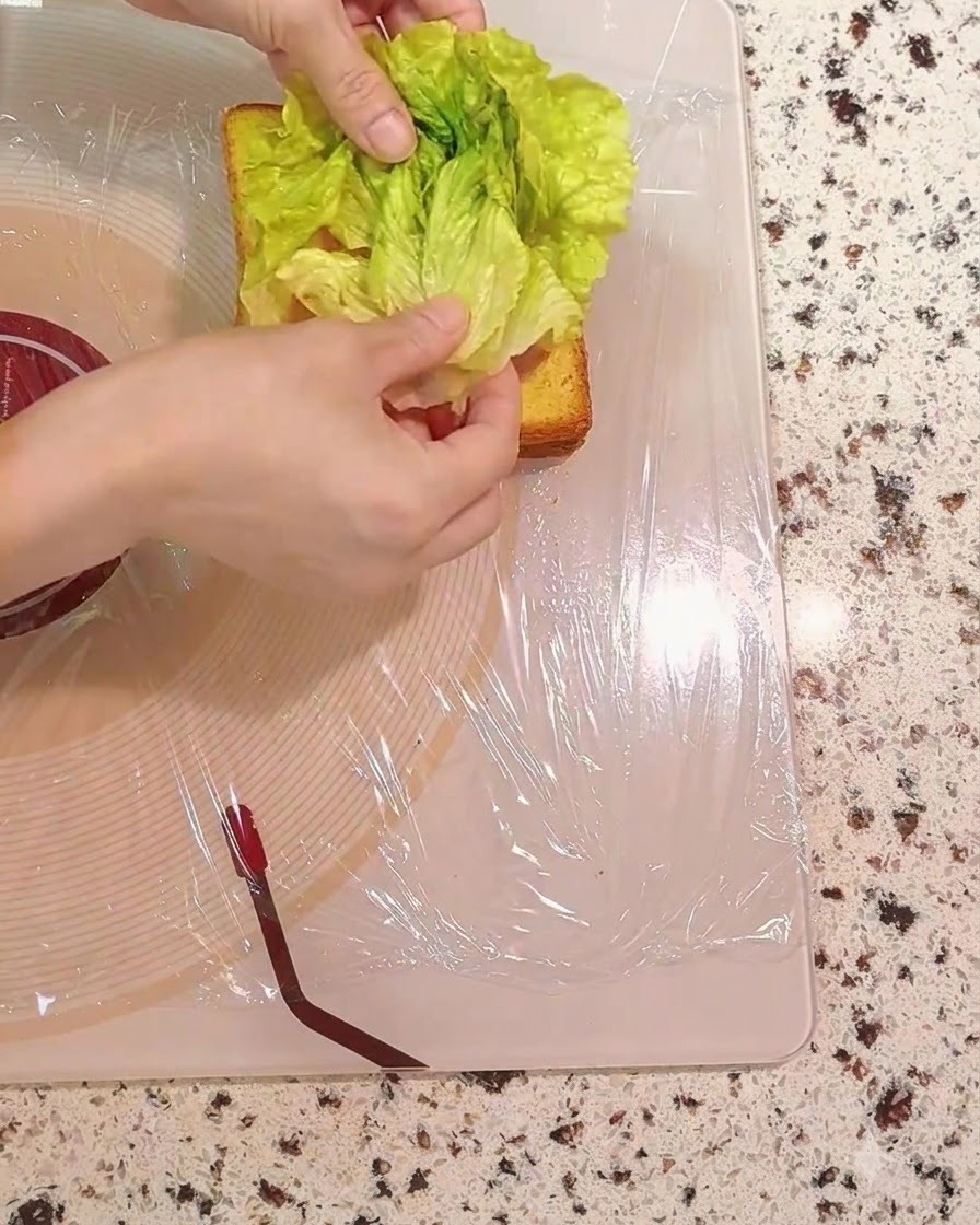 Des feuilles de laitue verte fraîche placées sur les couches du sandwich.