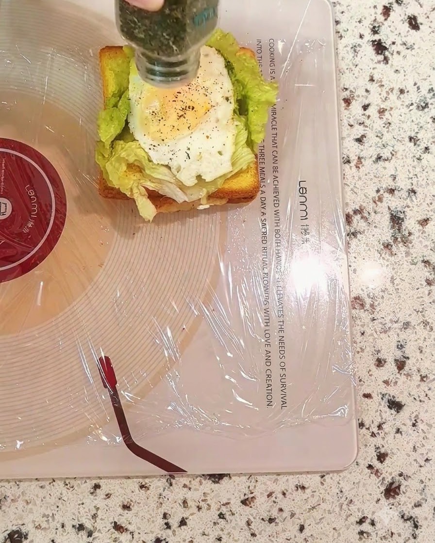 Saupoudrage de persil séché à partir dun flacon sur la couche dœuf du sandwich.