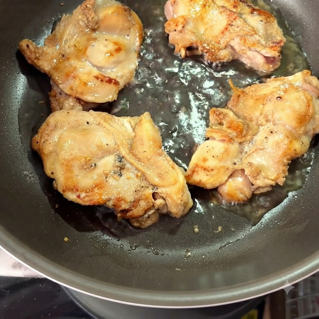 De leau chaude versée dans une poêle entourant des hauts de cuisse de poulet saisis.
