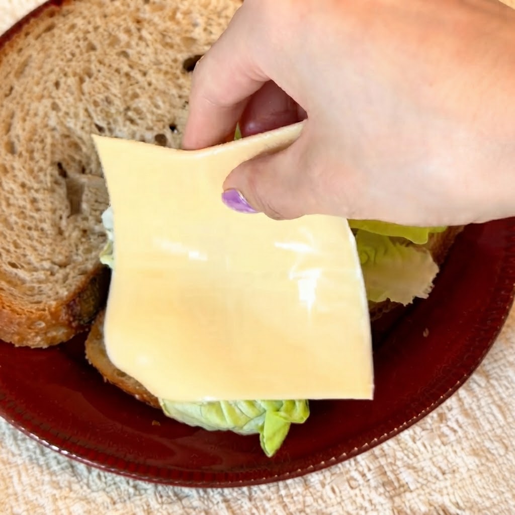 Deux tranches de fromage jaune allégé délicatement posées sur la laitue verte croustillante.