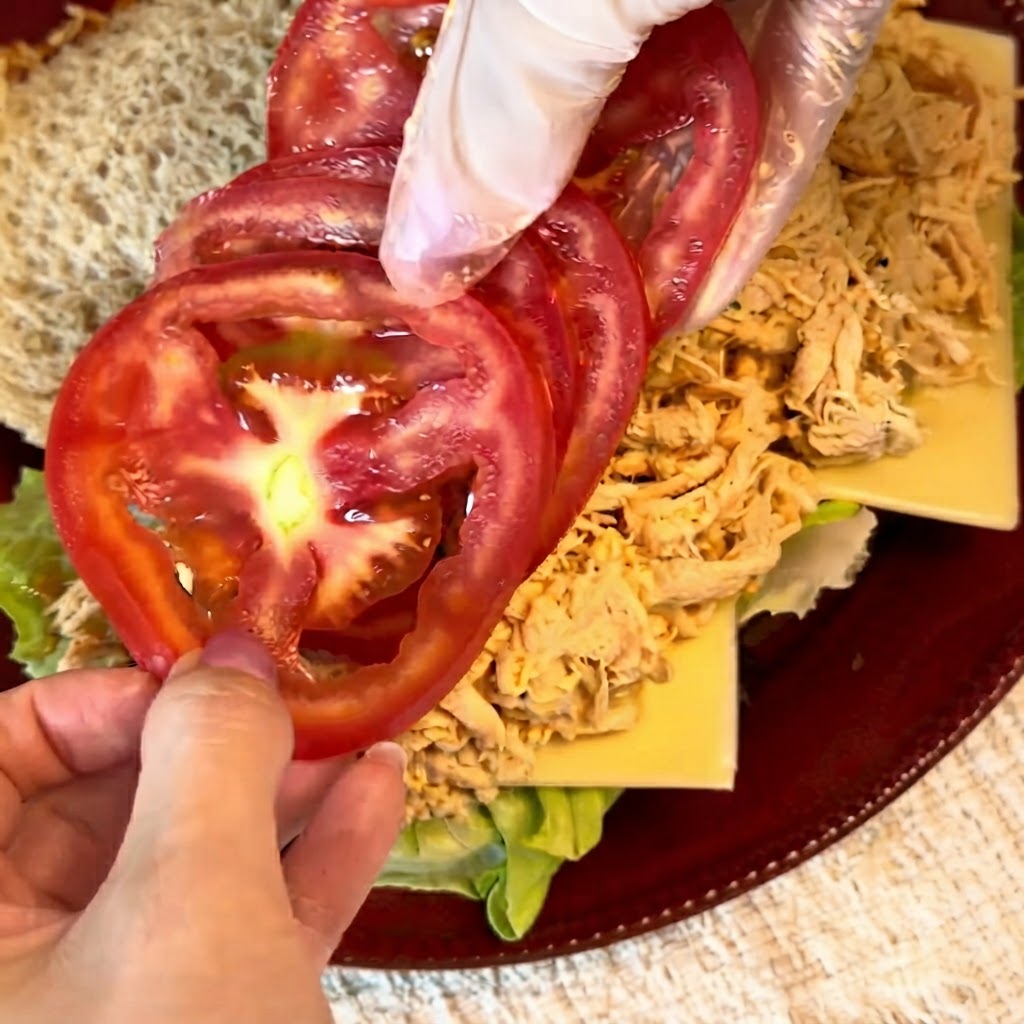 Des tranches de tomates rouges fraîches soigneusement disposées sur la garniture de poulet effiloché.