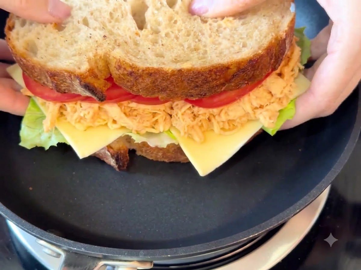 Le sandwich complet en cours de cuisson dans une poêle noire à feu doux.