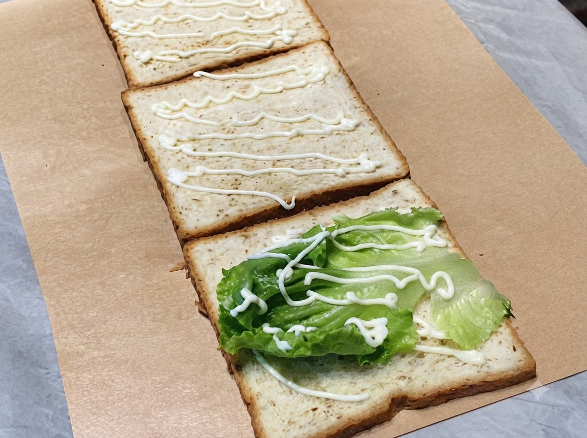 Tranches de concombre vert frais disposées sur la deuxième tranche de pain avec un filet de mayonnaise.