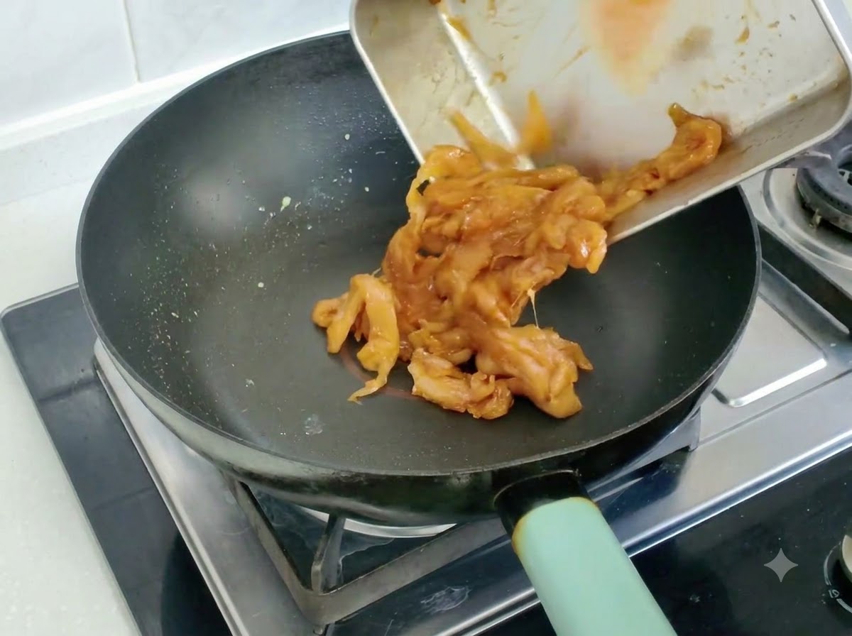 Morceaux de poulet marinés versés et sautés dans une poêle.