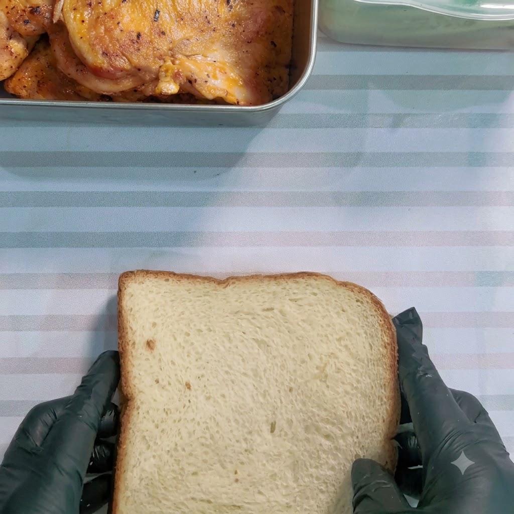 Un couteau à dent coupant un sandwich enveloppé en diagonale sur une surface rayée.