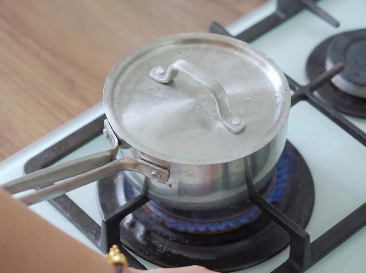 Une casserole couverte sur une cuisinière allumée avec de la vapeur séchappant, cuisant la poitrine de poulet.