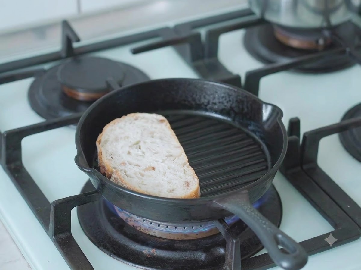 Une tranche de pain au levain en train de griller dans une poêle-gril en fonte chaude sur la cuisinière.