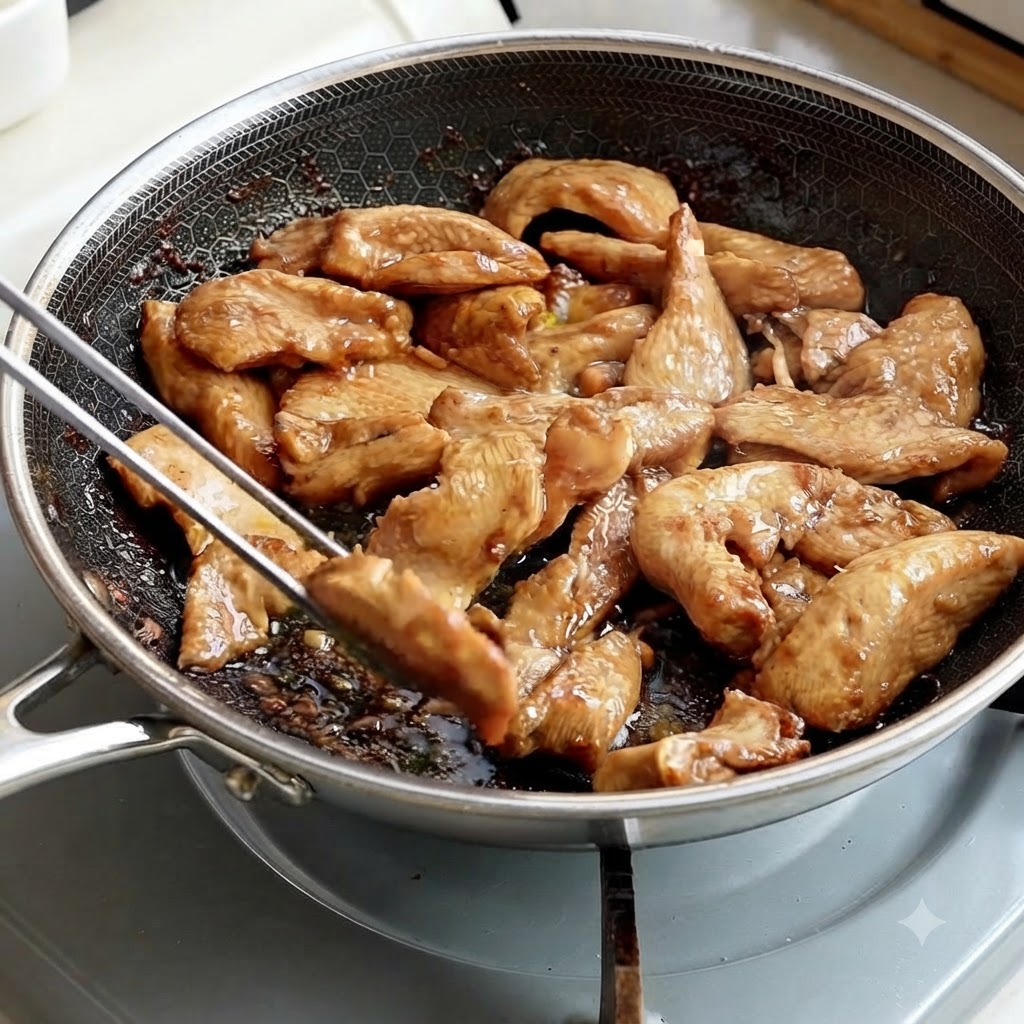 Des pinces en métal ramassant des lamelles de poulet cuites dune poêle.