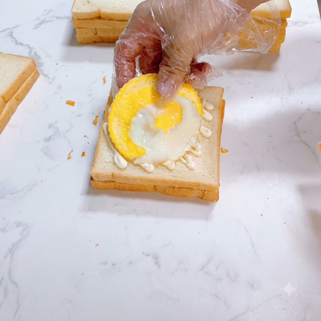 Un œuf au plat positionné soigneusement sur du pain blanc tartiné de mayonnaise.