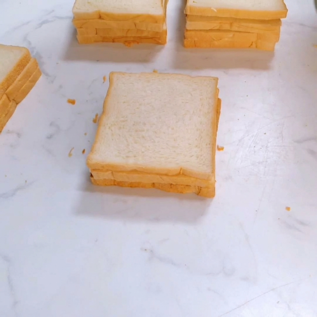 Une troisième tranche de pain de mie carré placée sur le dessus de la pile de sandwichs.