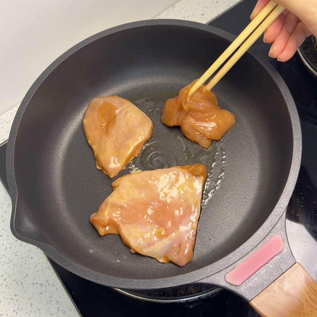 Morceaux de blanc de poulet dorés cuisant dans une poêle.