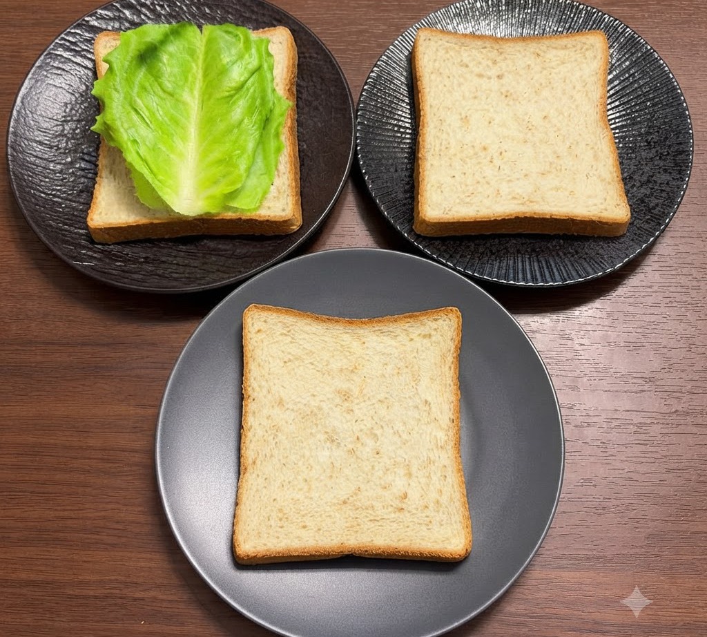 Feuilles de laitue verte fraîche disposées soigneusement sur des tranches de pain complet placées sur des assiettes noires.