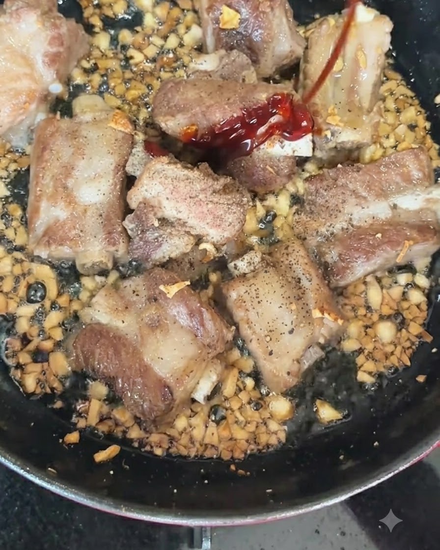 Piments rouges et verts ajoutés dans une poêle chaude contenant des côtes de porc en train de saisir et de lail haché.