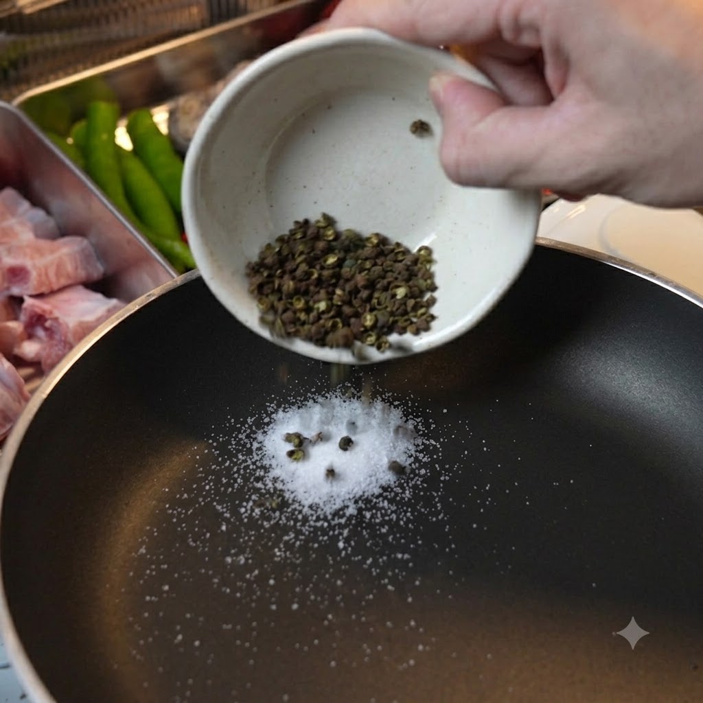 Poivre vert du Sichuan et sel grossier versés dans une poêle noire pour torréfaction à sec.