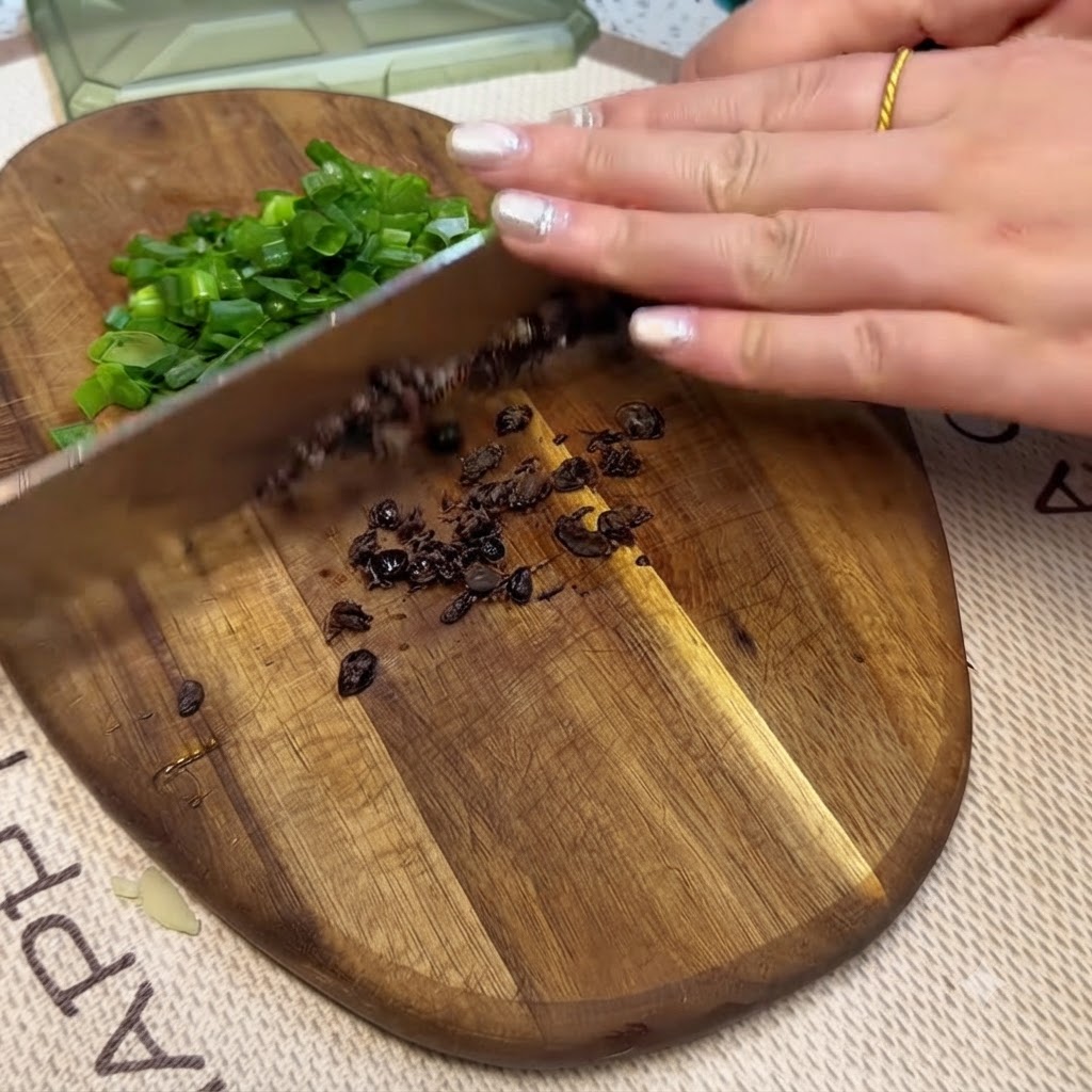 Haricots noirs fermentés et oignons verts hachés émincés sur une planche à découper en bois avec un couteau.