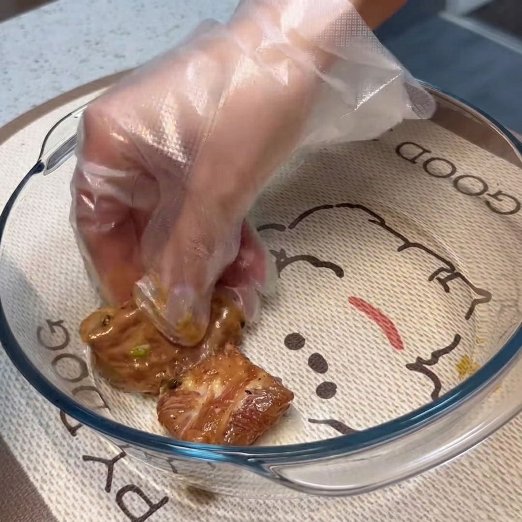 Travers de porc marinés disposés en une seule couche plate à lintérieur dun plat de cuisson en verre transparent.