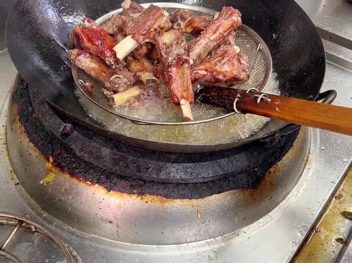 Côtes de porc frites retirées de lhuile chaude à laide dun panier en fil de fer.