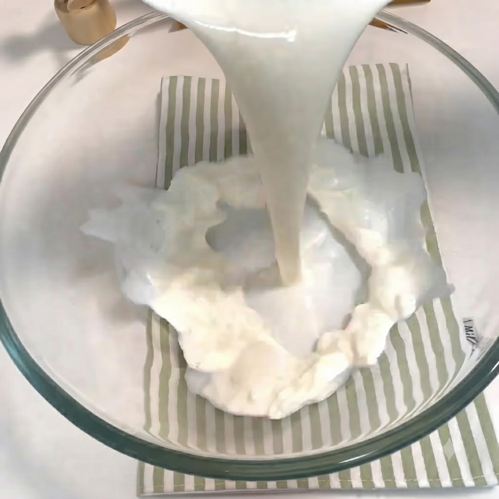 Du lait, du sucre, de la levure et un œuf versés et fouettés ensemble dans un bol en verre.