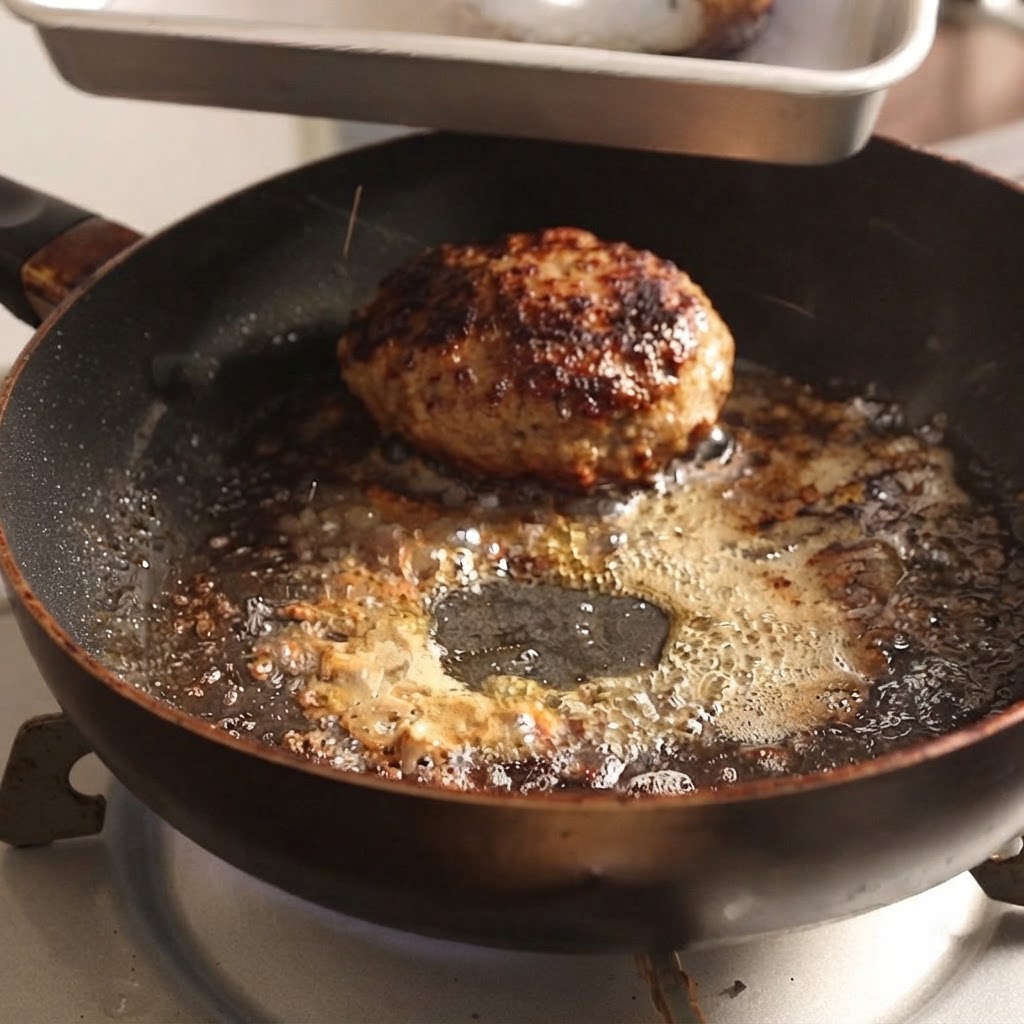 Des steaks hachés retirés dune poêle chaude à laide de pinces en métal.