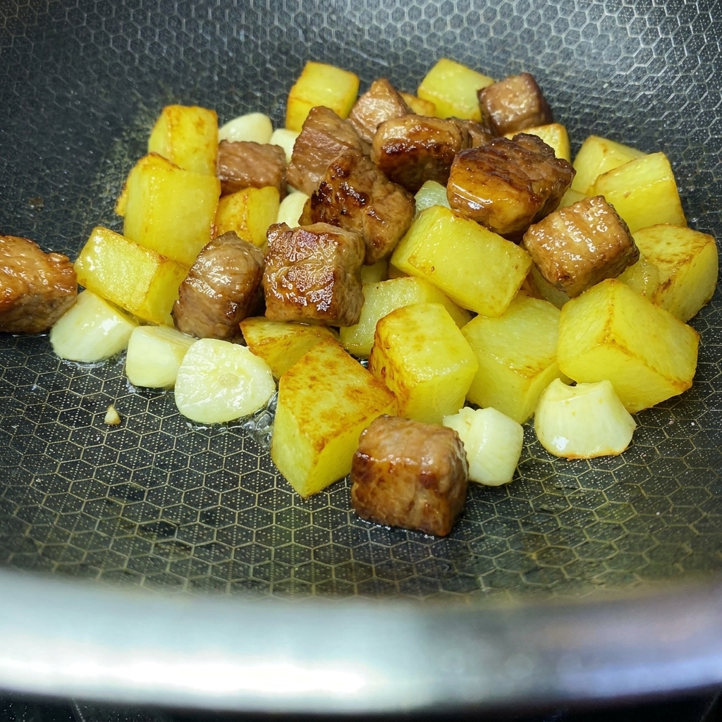Cubes de pommes de terre dorés et croustillants et cubes de porc saisis combinés ensemble dans un wok.