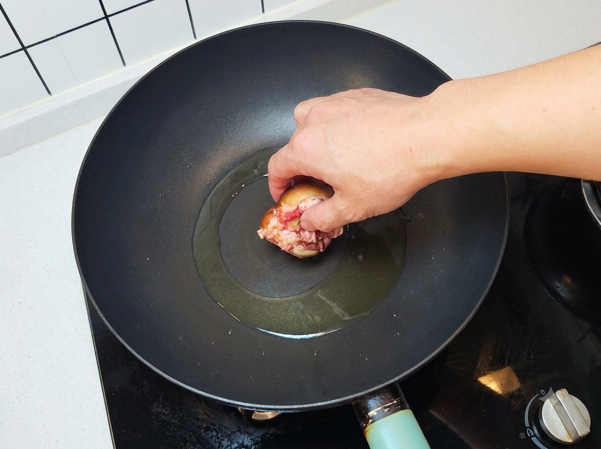 Un champignon farci déposé côté viande vers le bas dans un wok huilé bien chaud.