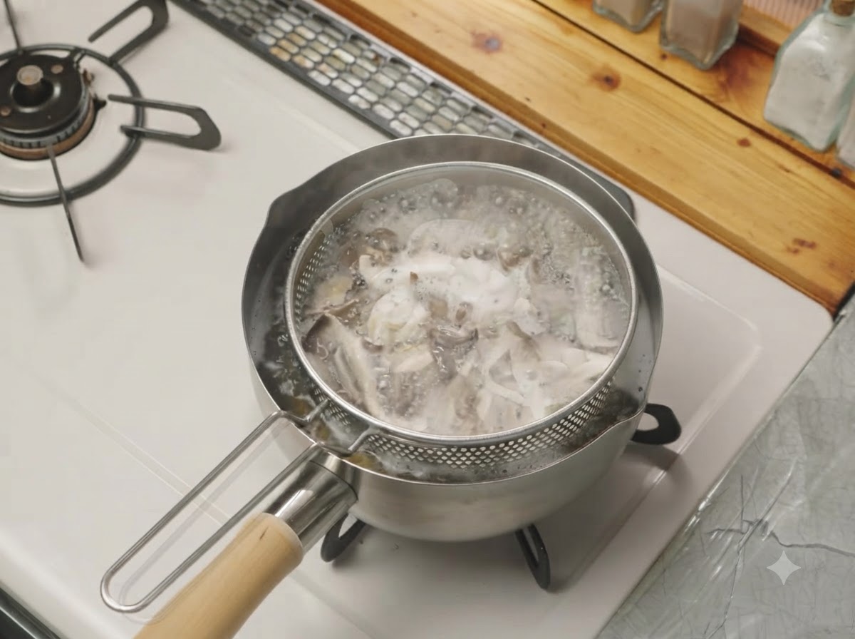 Des champignons effilochés en train de bouillir dans un panier de passoire en treillis placé dans une casserole deau sur le feu.