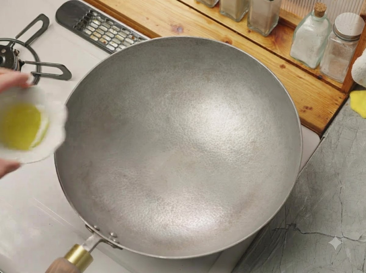 Un petit bol versant de lhuile de cuisson dans un wok chaud et vide.