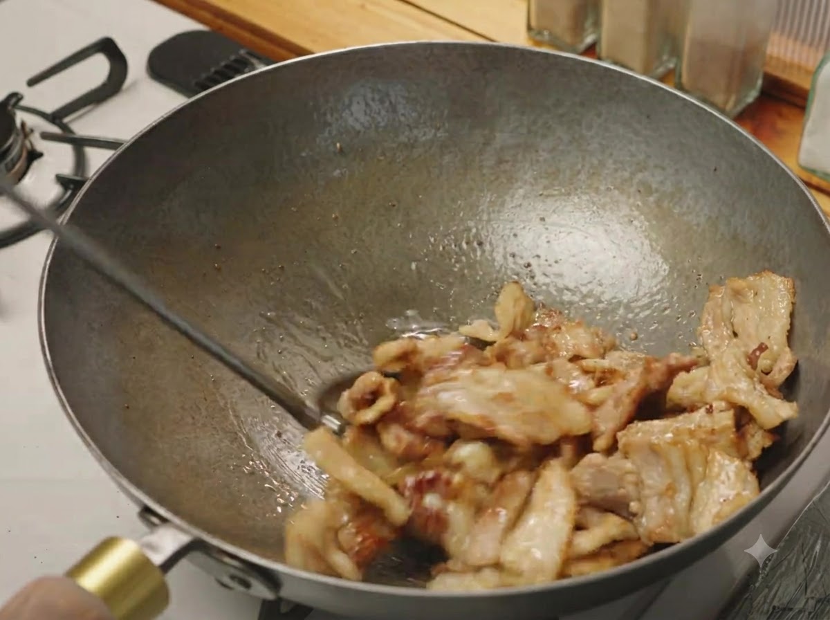 Des tranches de poitrine de porc sautées dans un wok jusquà ce quelles soient légèrement dorées et grésillantes.