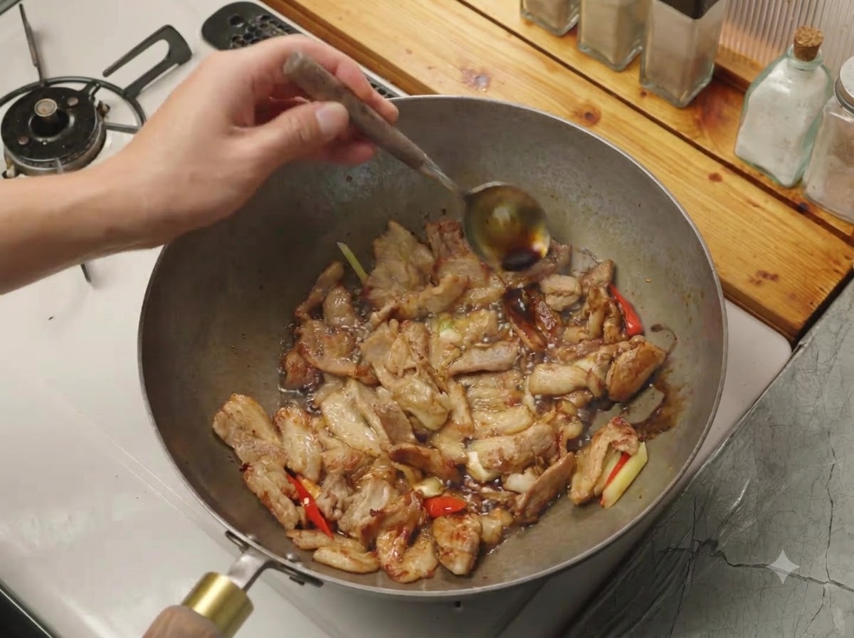 De la sauce soja versée à la cuillère sur le bord chaud dun wok contenant de la viande et des aromates.