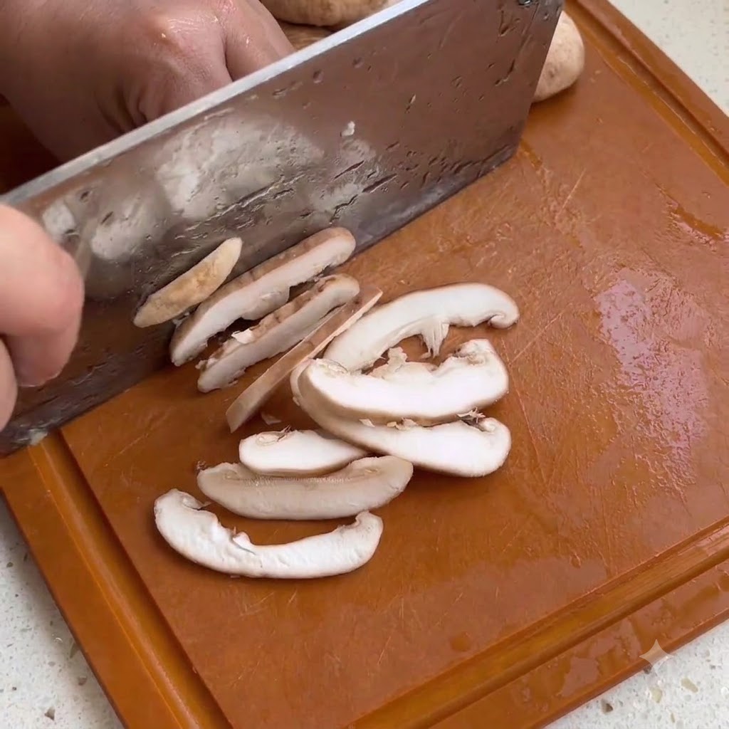 Tranches de champignons shiitake coupées sur une planche à découper en bois avec un couteau de cuisine.