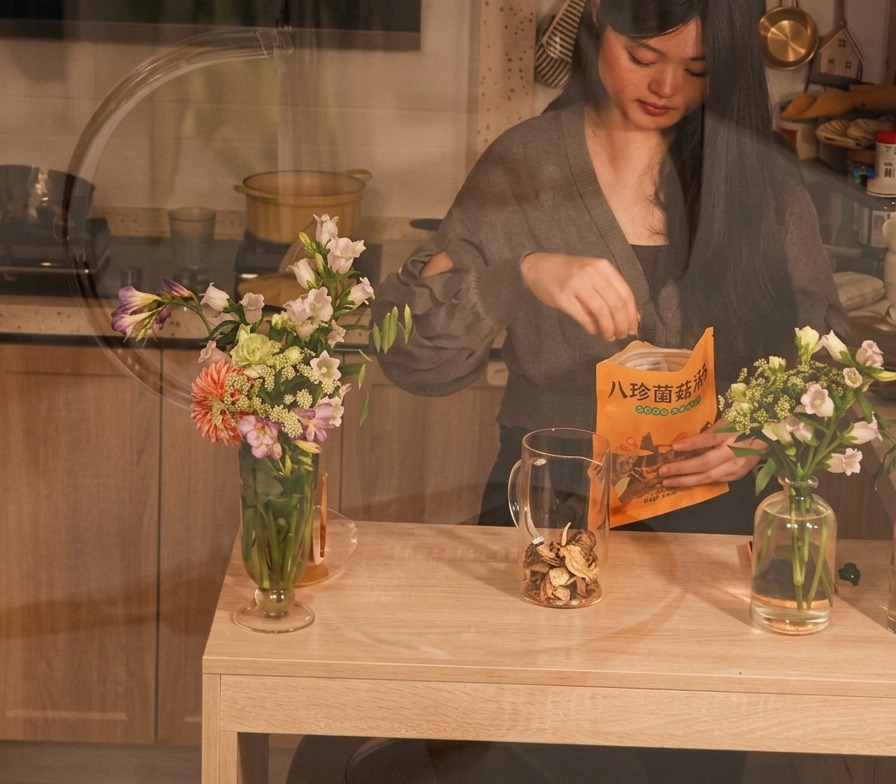 Une personne plaçant des champignons séchés dun sachet dans un pichet en verre transparent sur une table en bois.