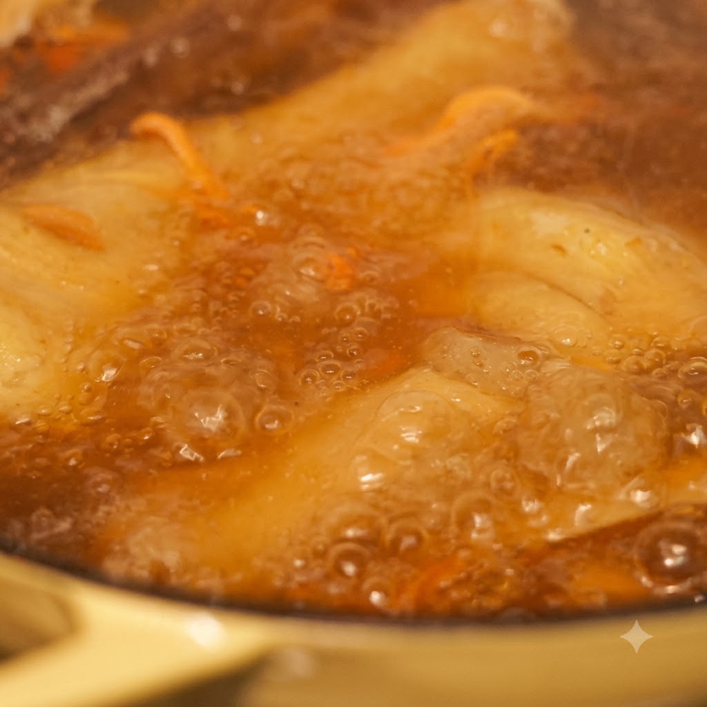 Gros plan sur des nouilles et des légumes cuisant dans un bouillon frémissant.