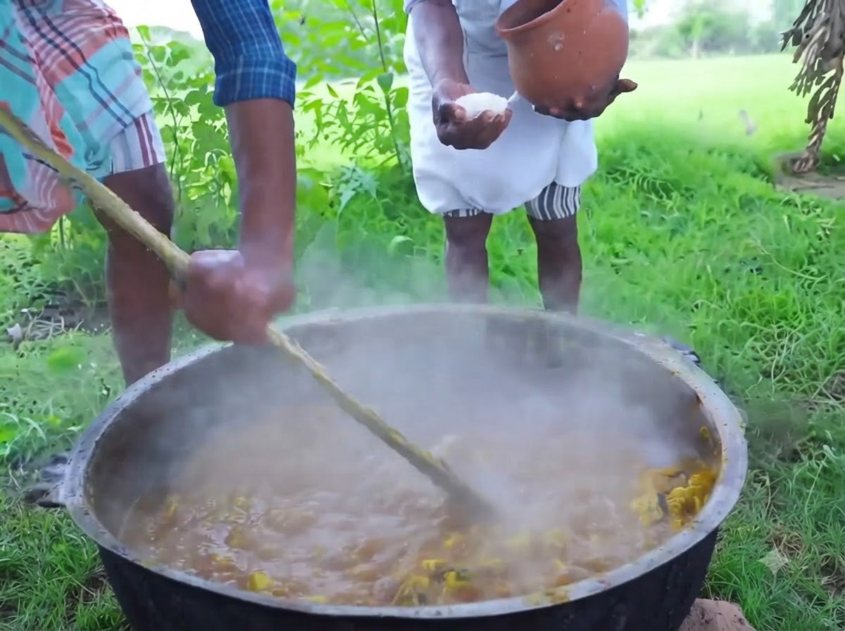 Une personne versant du sel de cristal blanc dun pot en argile sur un mélange fumant dans une grande cocotte en fer.