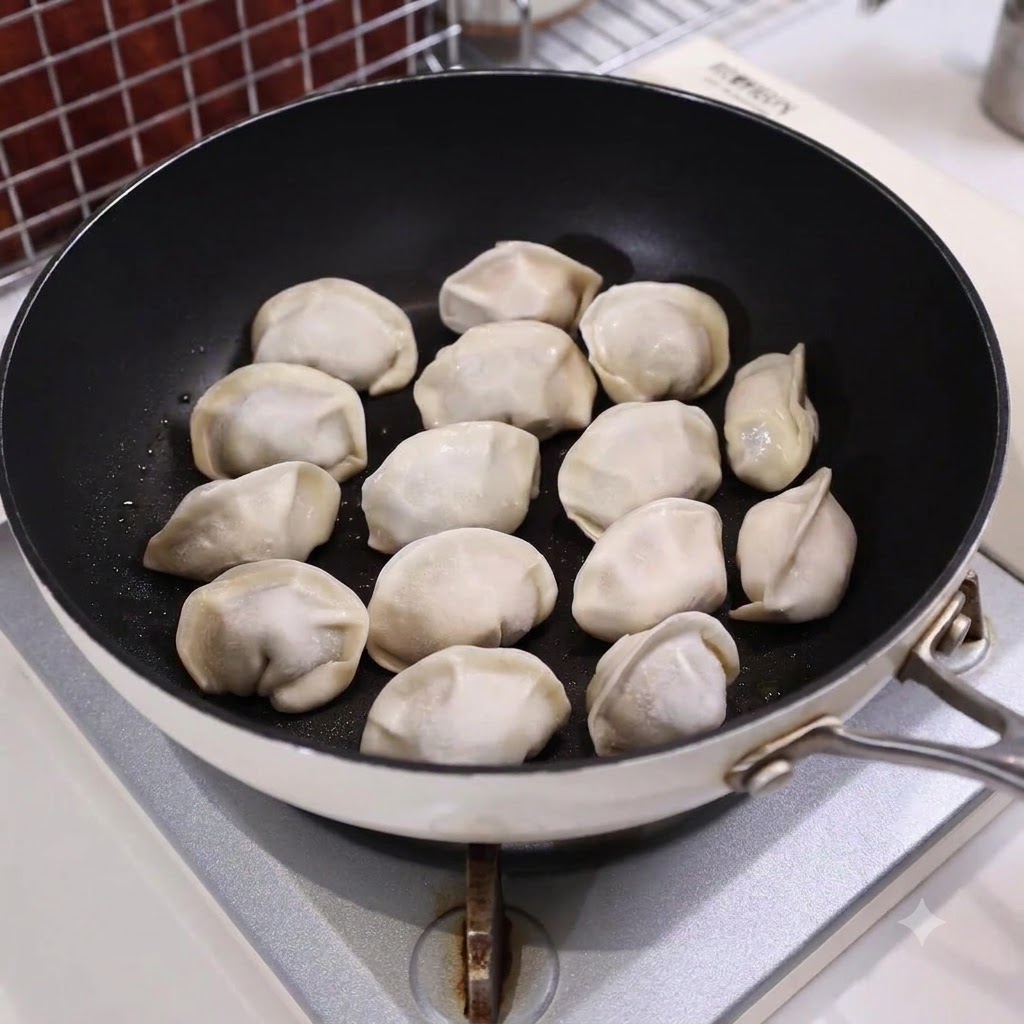 Une poêle remplie de raviolis disposés et partiellement immergés dans leau sur une gazinière.