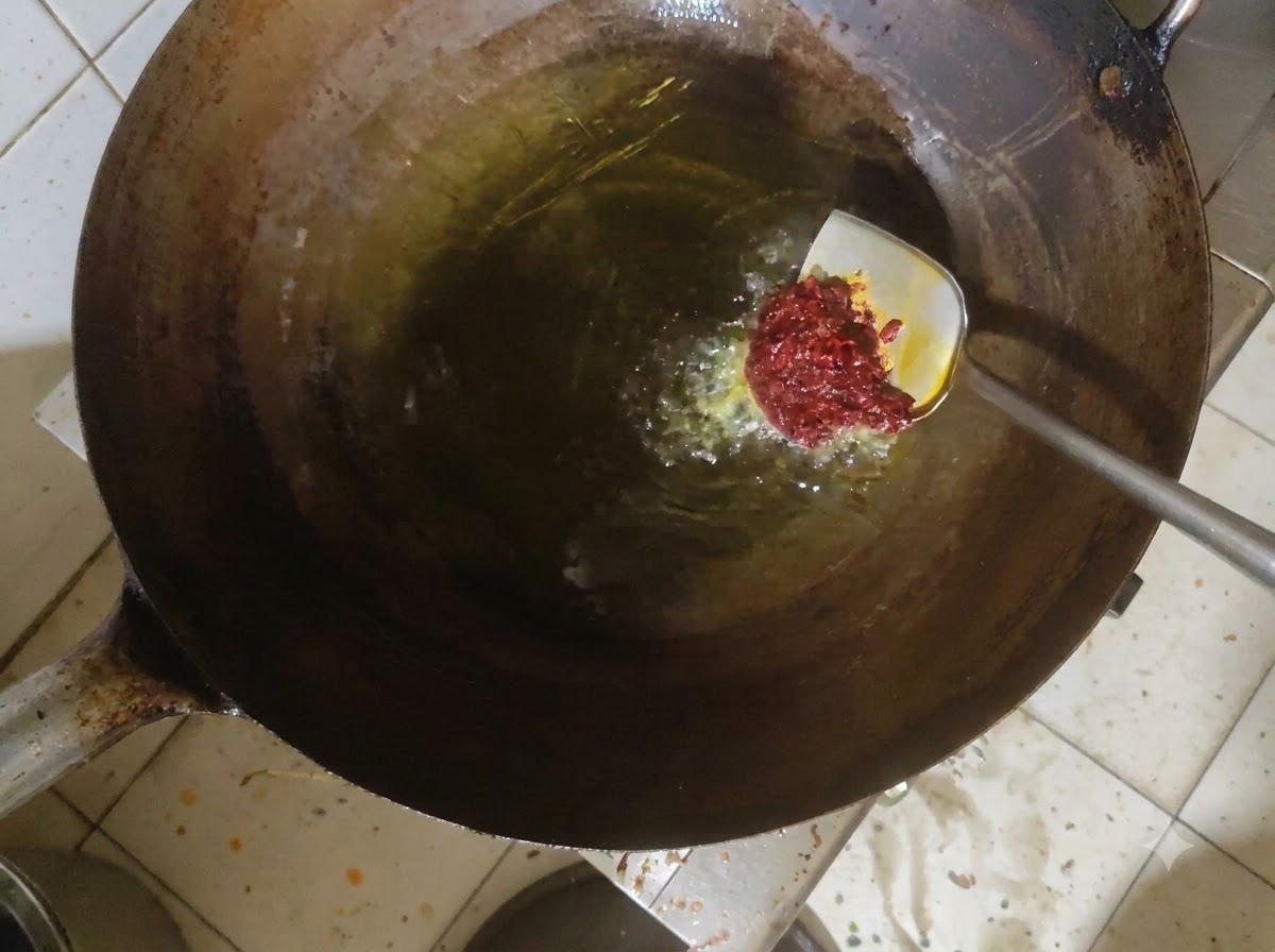 Pâte doubanjiang incorporée à lhuile chaude dans un wok.