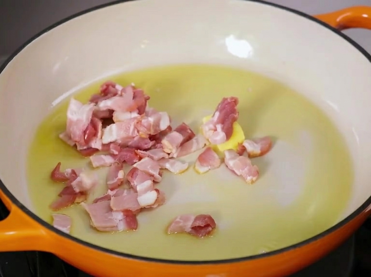 Des morceaux de bacon qui grésillent dans une poêle avec du beurre fondu et de lhuile dolive.