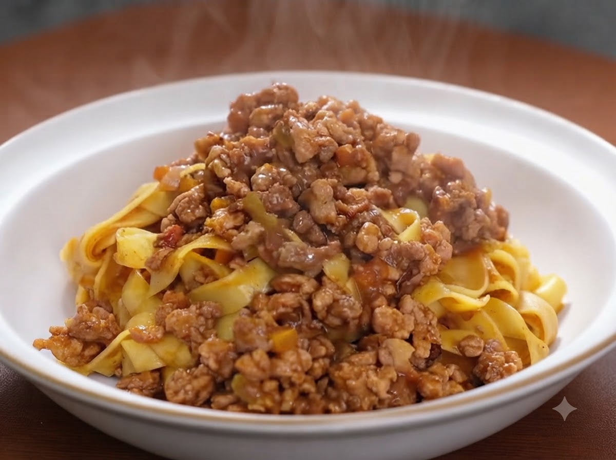 Du concentré de tomate incorporé dans un mélange de viande dorée et de légumes dans une poêle de cuisson.