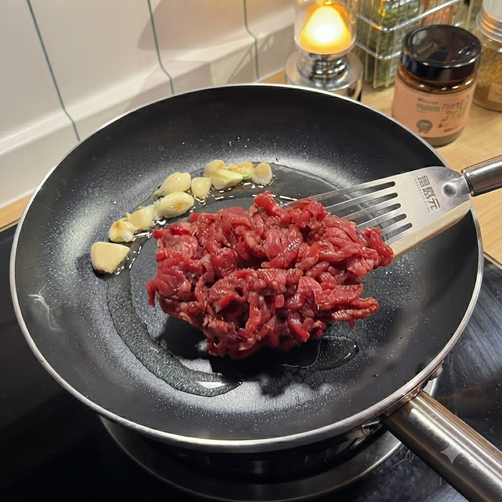 Des lanières de bœuf crues et assaisonnées placées avec une spatule dans une poêle chaude contenant de lail.