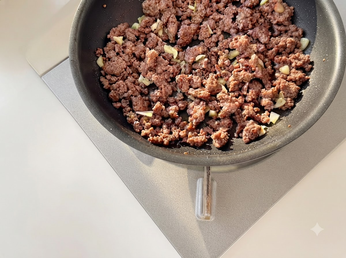 De lail haché et des tomates en dés sautés ensemble avec du bœuf haché doré dans une poêle.